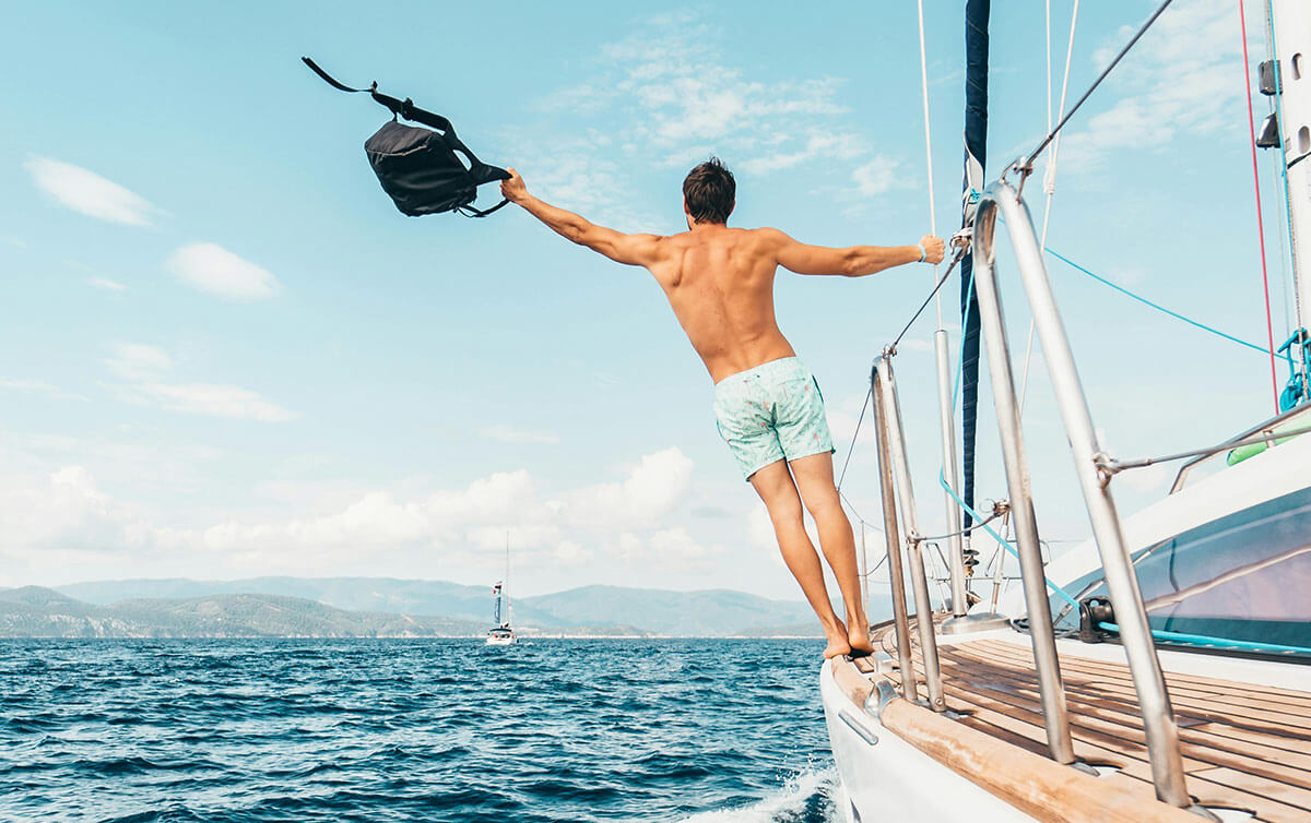 Wealthy man waving backpack from yacht - signifying freedom from money